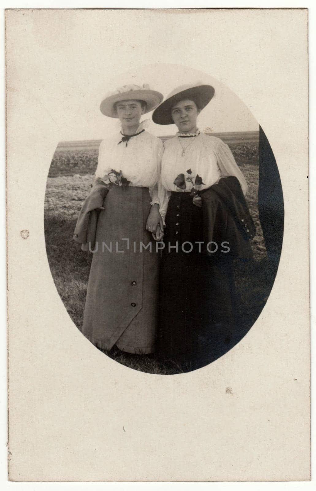 GERMANY - SEPTEMBER 24, 1916: Vintage photo shows young ladies wear period clothes. Photo is oval shaped. Retro black and white photography.