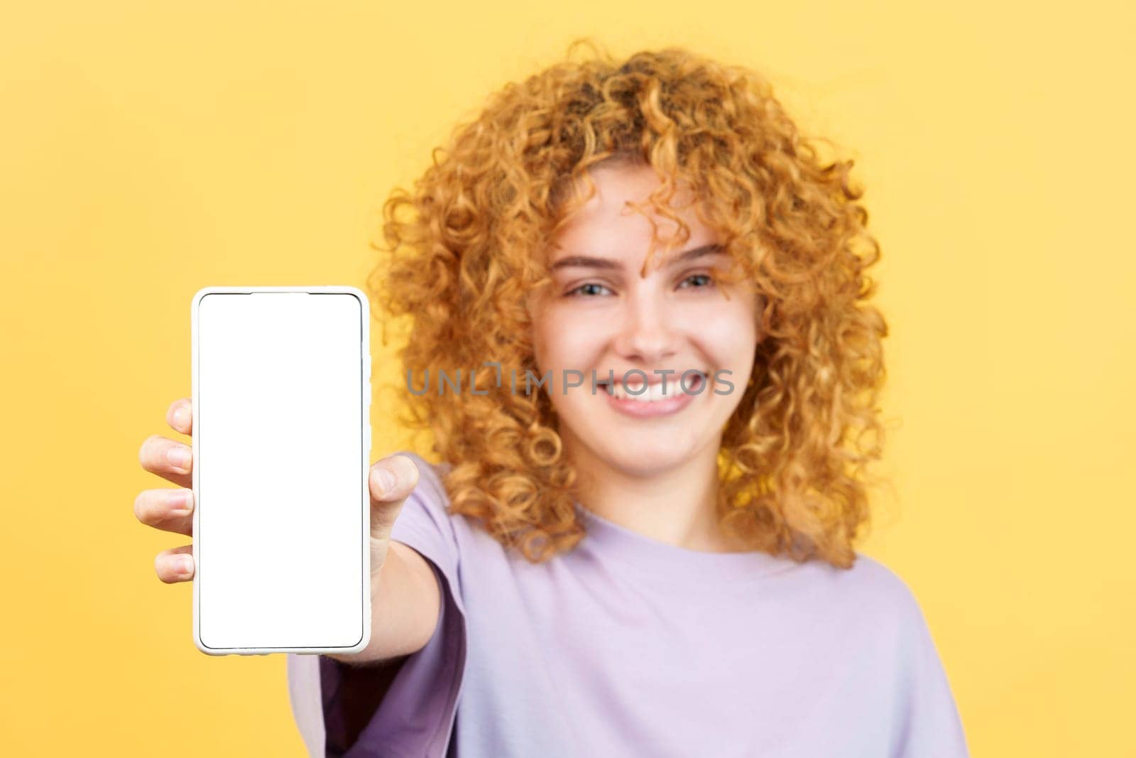 Studio image with yellow background of the blank screen of the mobile held by a young woman
