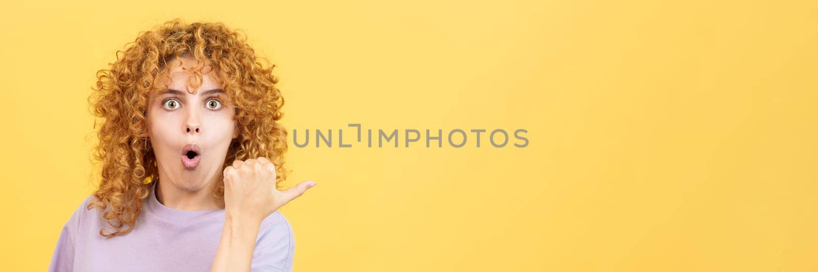 Woman with curly hair pointing surprised to the side by ivanmoreno