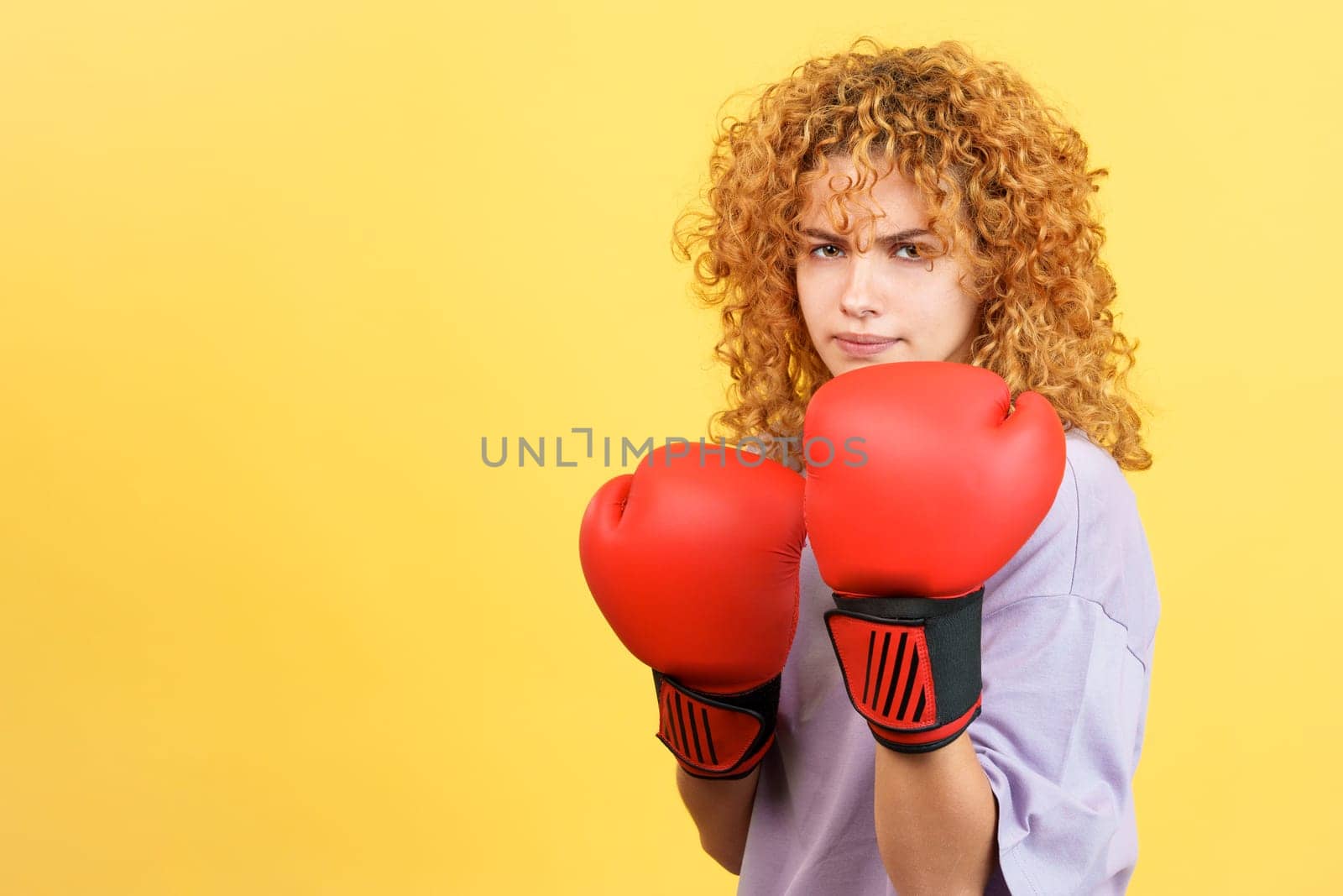Studio image with yellow background of a rude girl in boxing gloves looking at camera