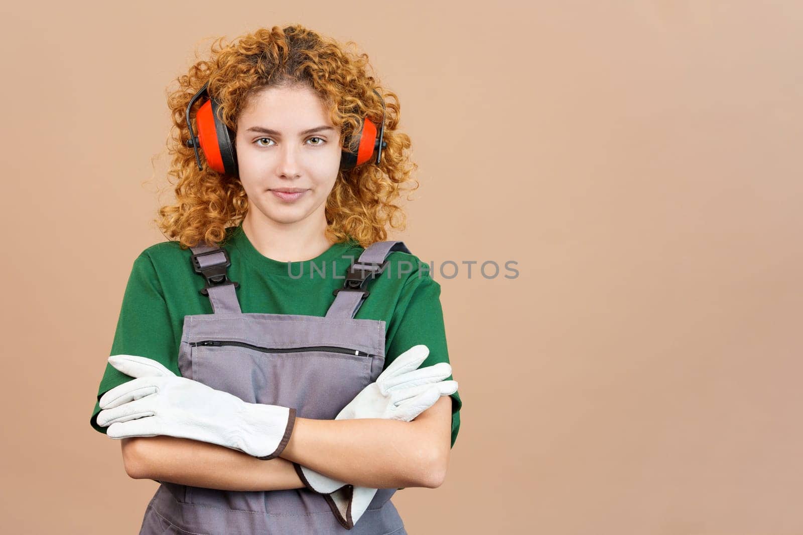 Studio image of a woman with curly hair carpentry worker with tools and work uniform