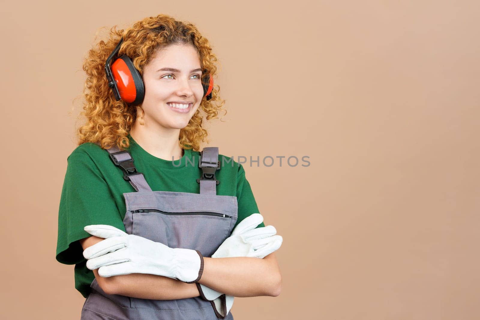 Studio image of a distracted woman carpentry worker with tools and work uniform