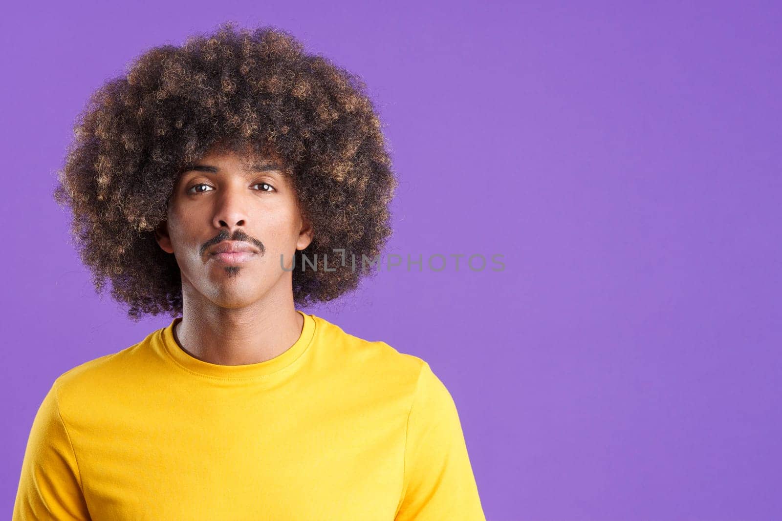 Cool african man with curly hair looking at the camera with a serious look in studio