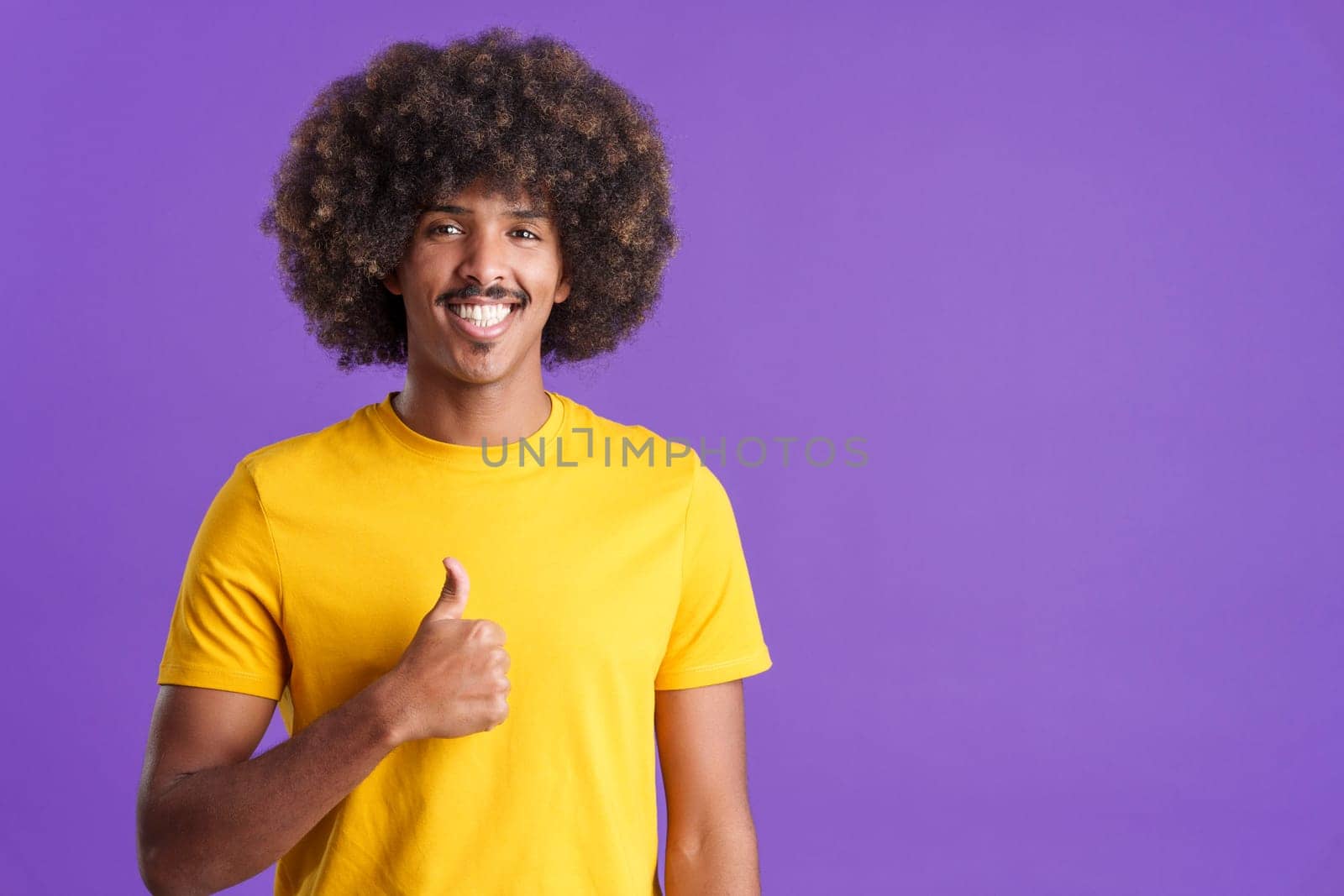 African man with curly hair gesturing agreement raising a thumb up in studio