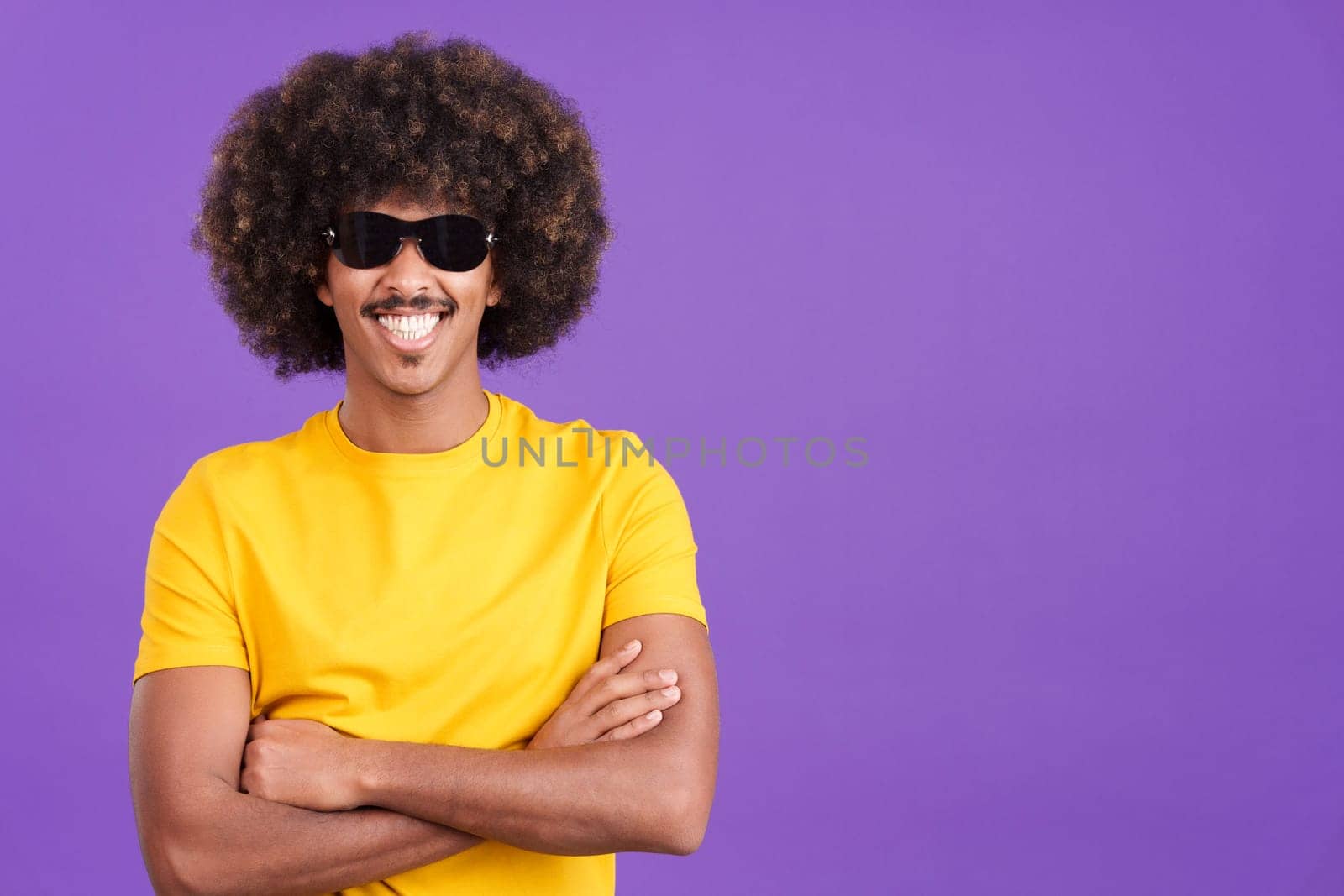 Happy african man with sunglasses standing with arms crossed and smiling at the camera in studio