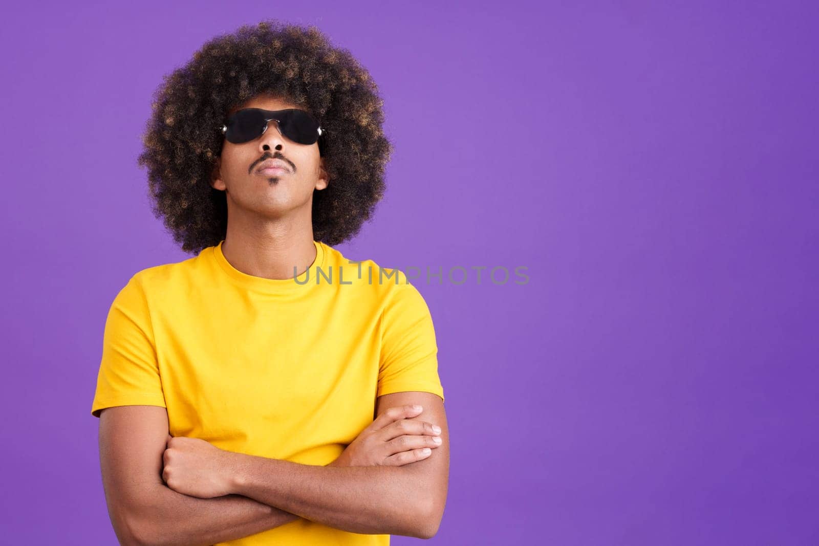 African man in cocky pose looking at camera with sunglasses on in studio