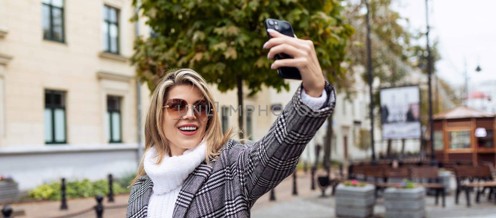 young woman model taking selfie with phone outdoors in spring by TRMK