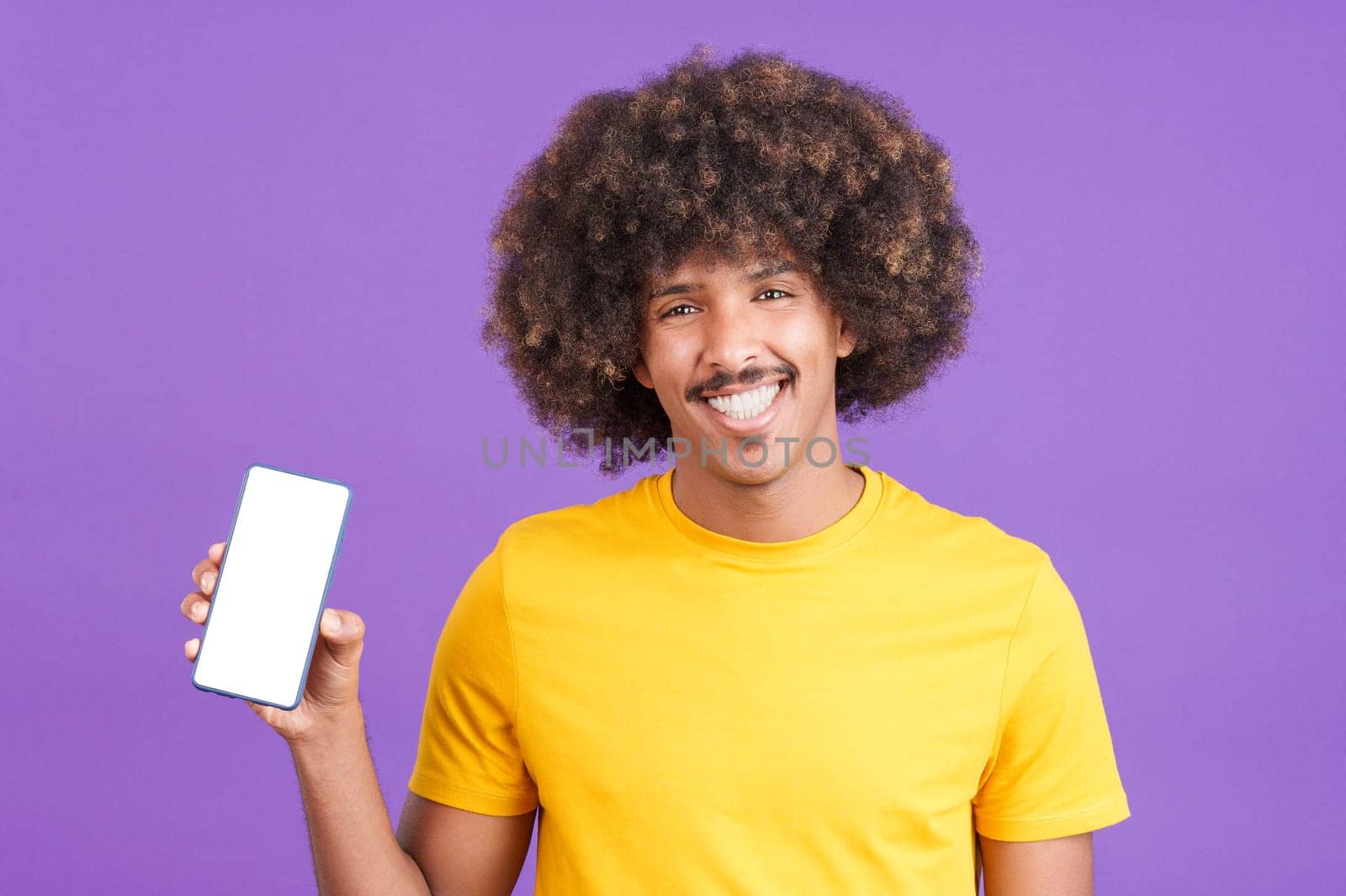 Happy african man holding a mobile with a blank screen. Purple background