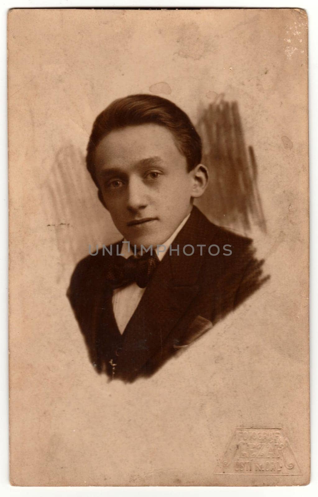 USTI NAD ORLICI, THE CZECHOSLOVAK REPUBLIC - CIRCA 1930s: Vintage photo shows a head of a young man. Original retro black and white photography. The jacket and bow tie are drawn to the head.