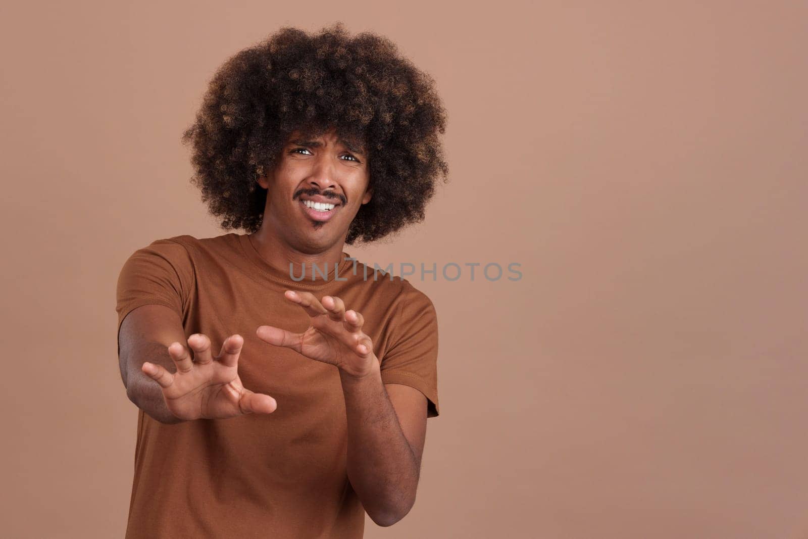 African man with curly hair gesturing with the hands in fear in studio