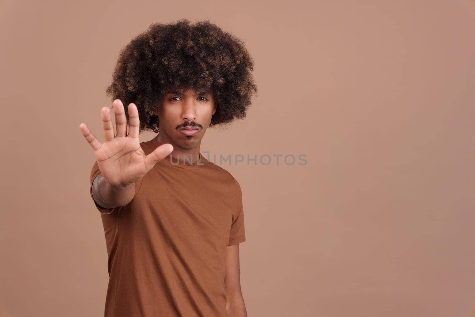 Serious african man gesturing prohibition with hand in studio. Stop concept