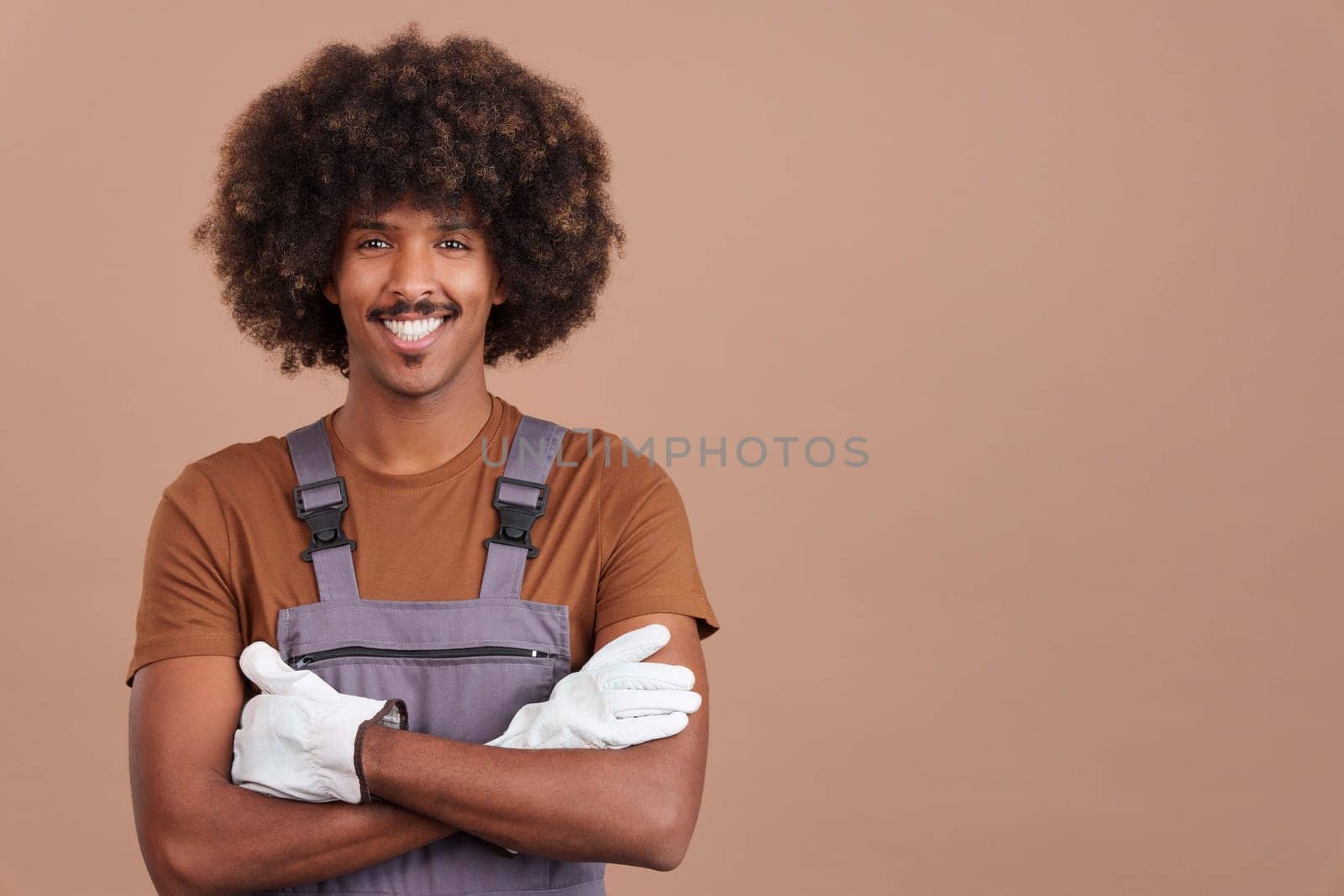 Friendly african man carpentry worker looking at the camera wearing a work uniform in studio