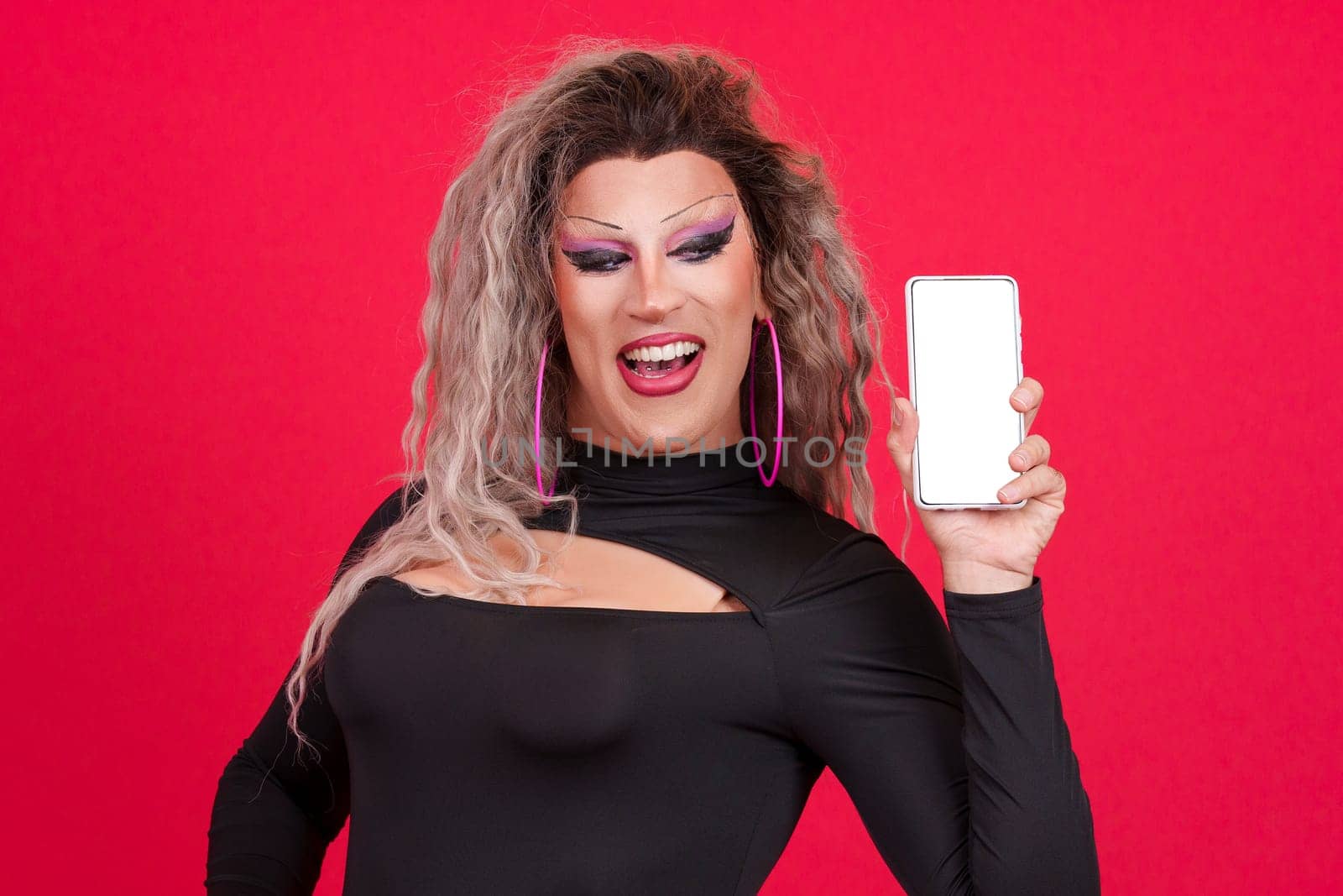 Blank screen of the mobile held by a transgender person dressed as drag queen in studio with red background