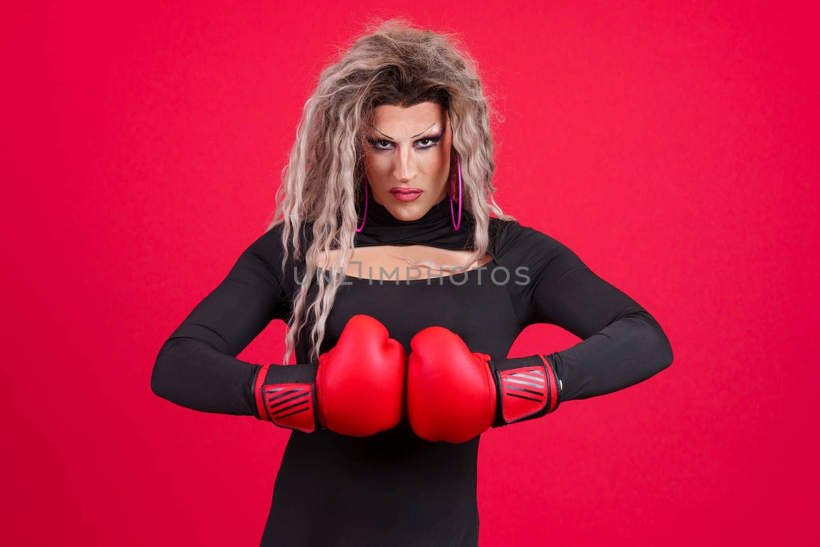 Transgender person with boxing gloves and defence attitude in studio in red background