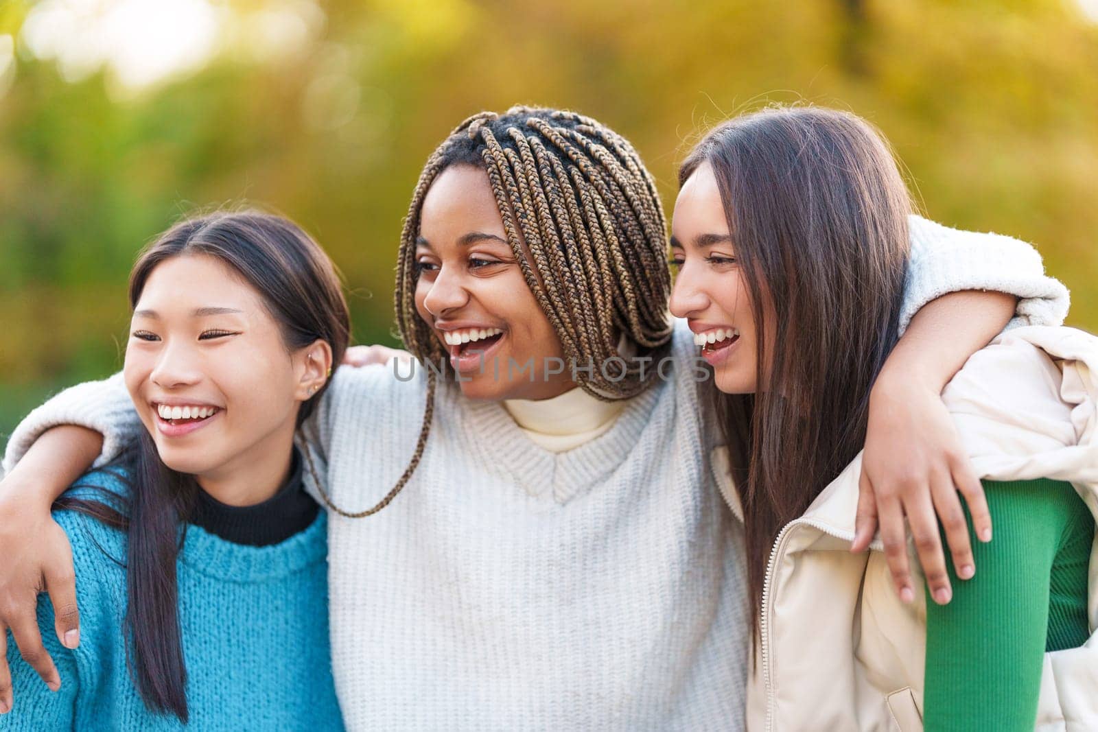 Multiethnic group of female friends embracing while smiling in the park