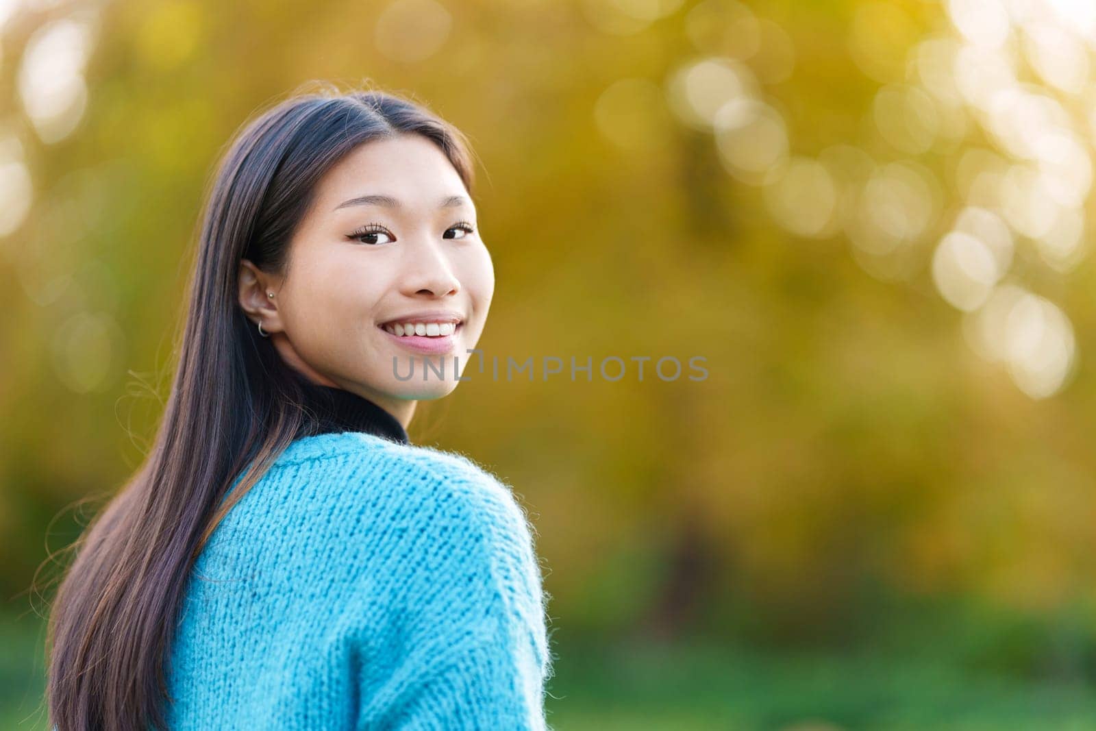 Happy asian woman turning to smile at the camera in a park