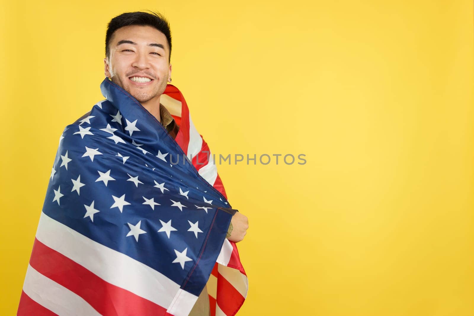 Happy chinese man wrapping with a United States national flag by ivanmoreno