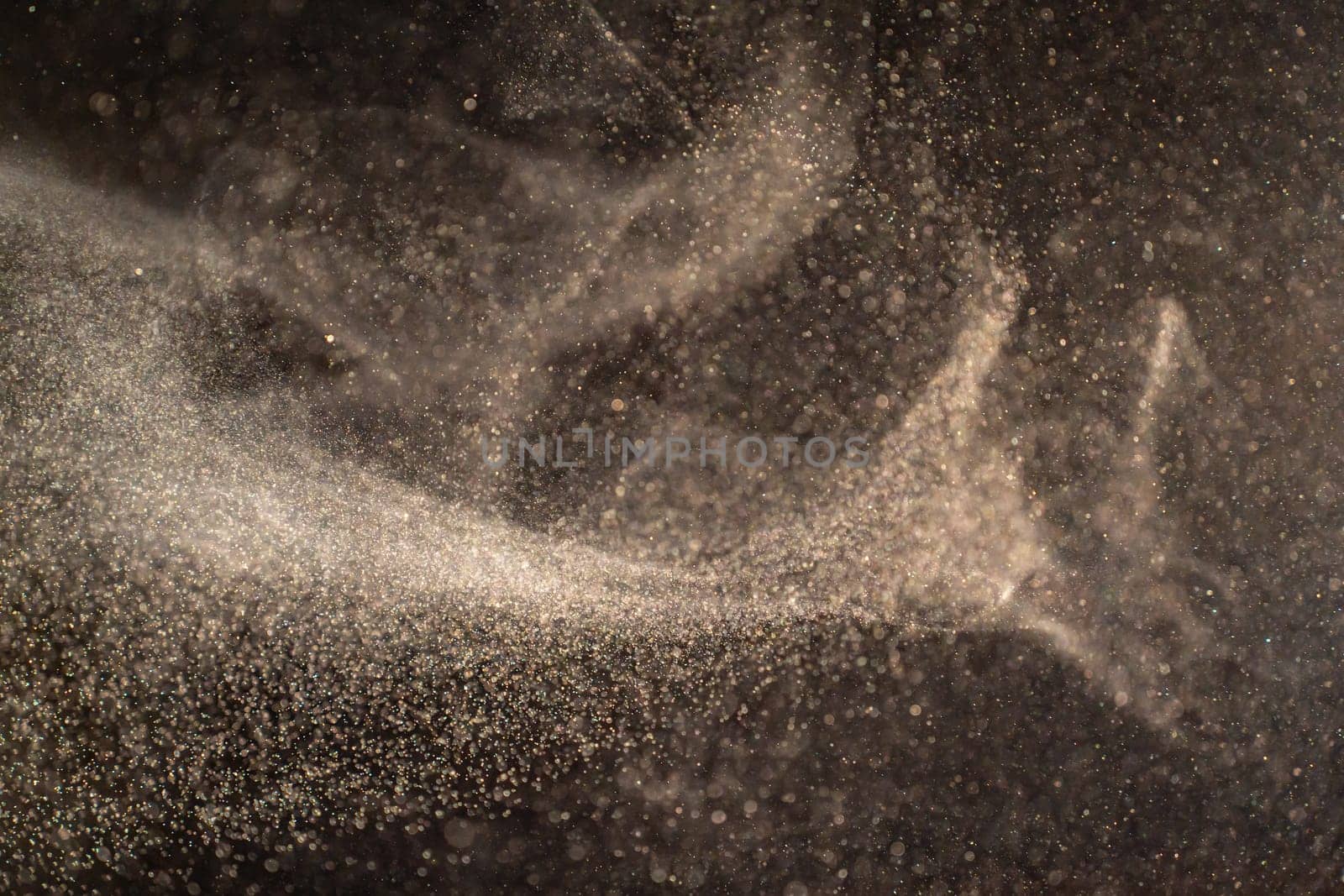 Organic dust particles floating on a light beam on black background. by PaulCarr