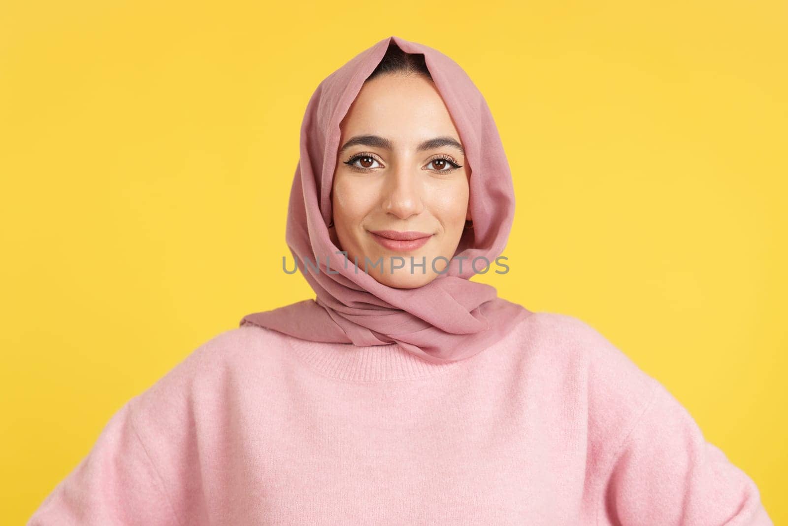 Beauty friendly muslim woman looking at camera in studio with yellow background