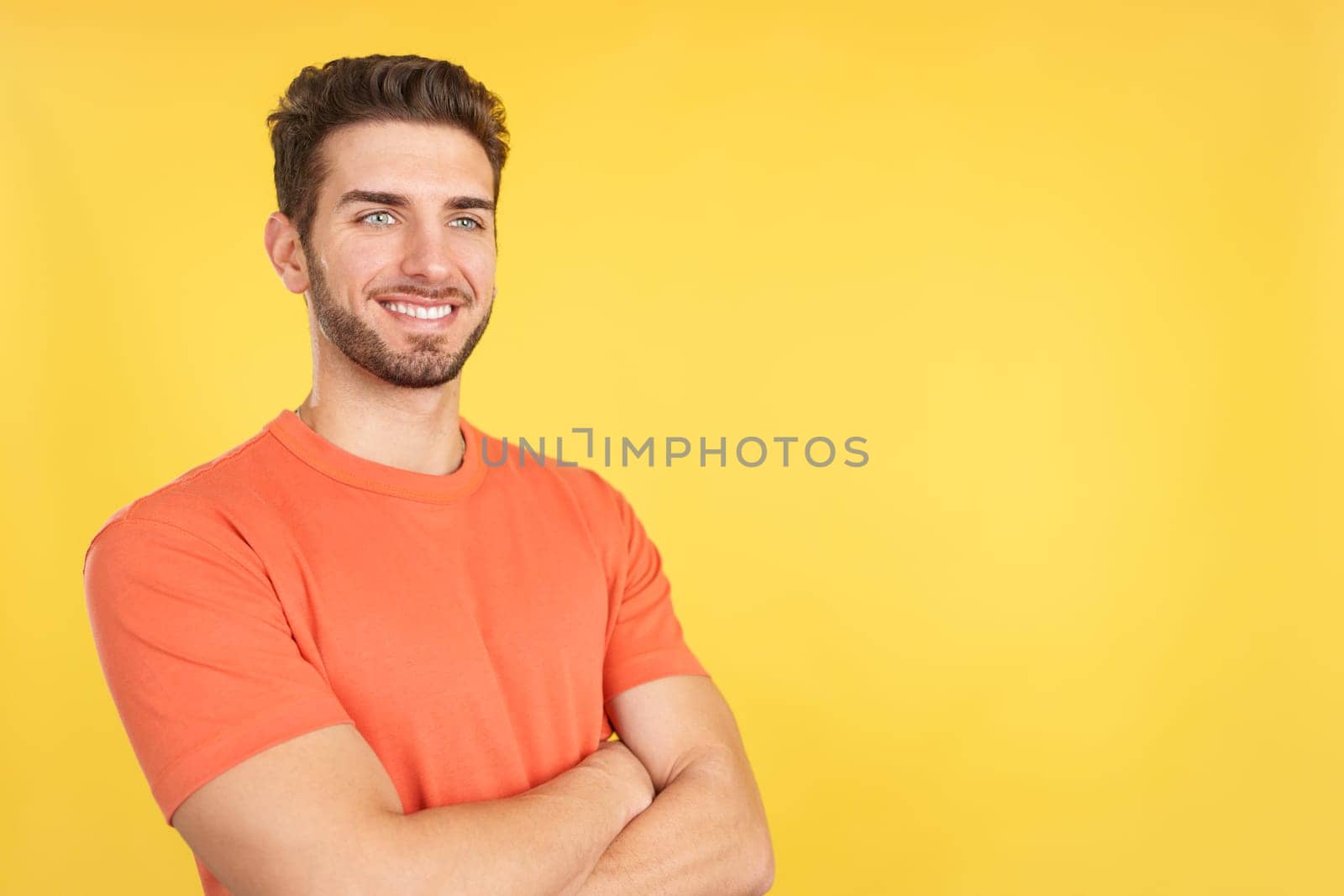 Happy caucasian man standing with arms crossed in studio with yellow background