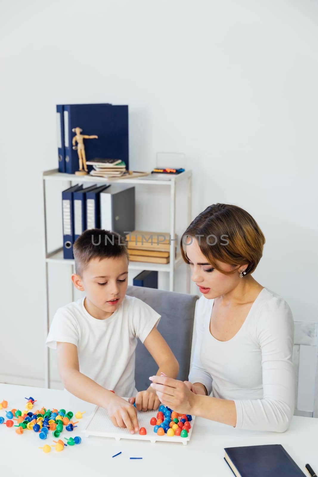 a child psychologist is engaged with a child in the office by Simakov