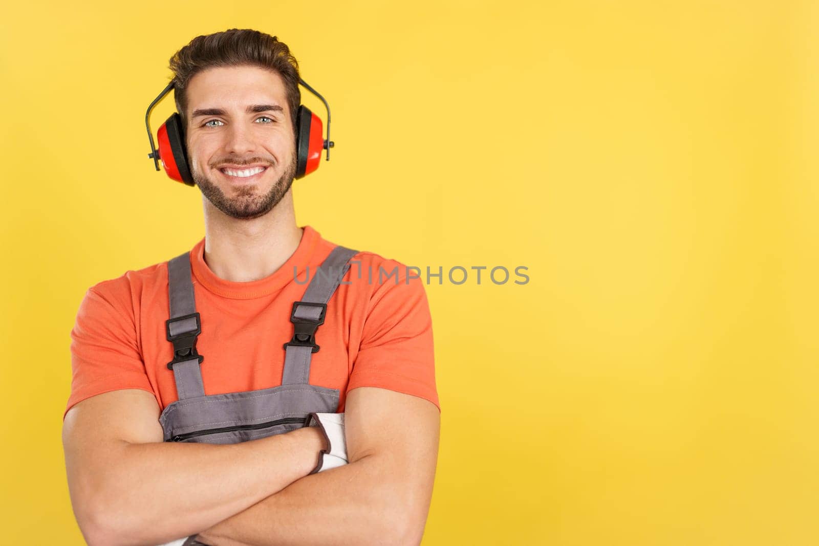 Friendly caucasian man carpentry worker in work uniform in studio with yellow background