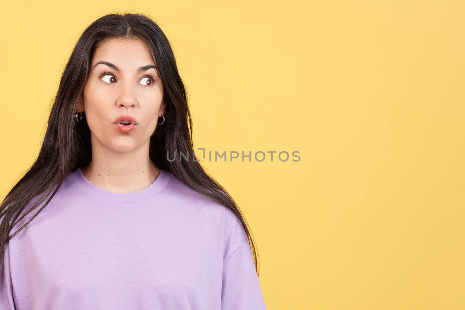 Surprised caucasian woman looking away in studio with yellow background