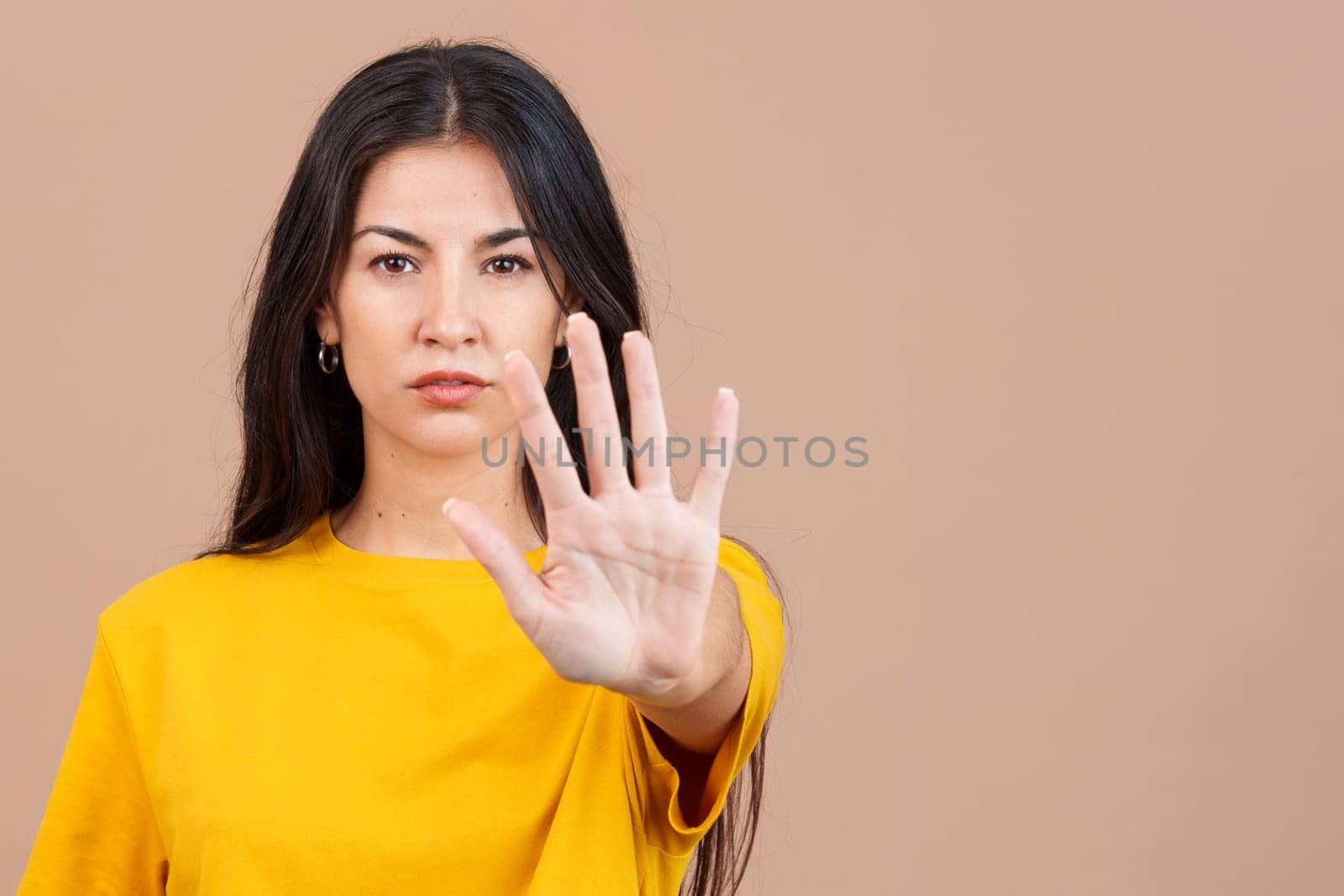 Caucasian woman gesturing prohibition with hand in studio with brown background