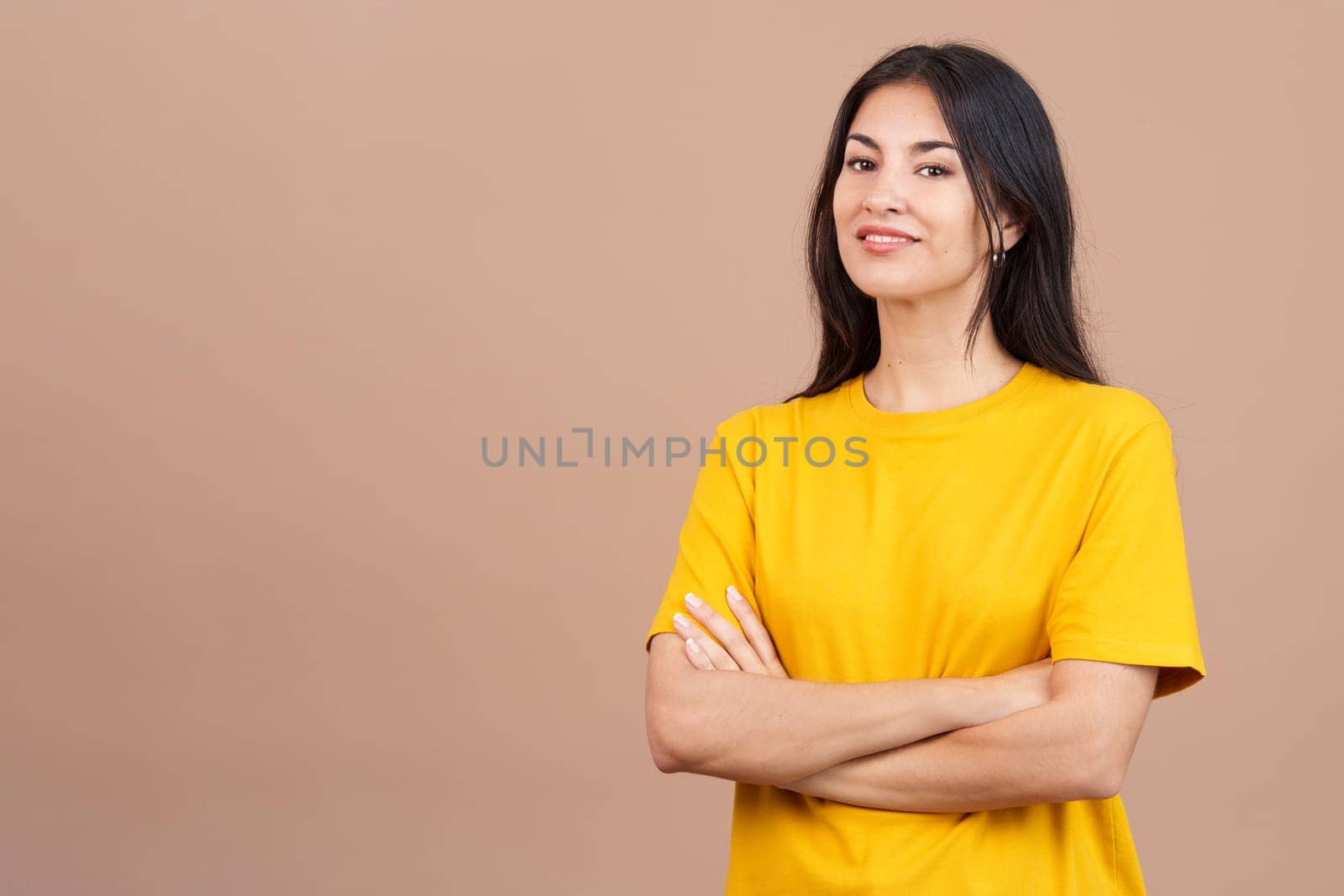 Beauty hispanic woman standing whit arms crossed smiling at the camera in studio with brown background