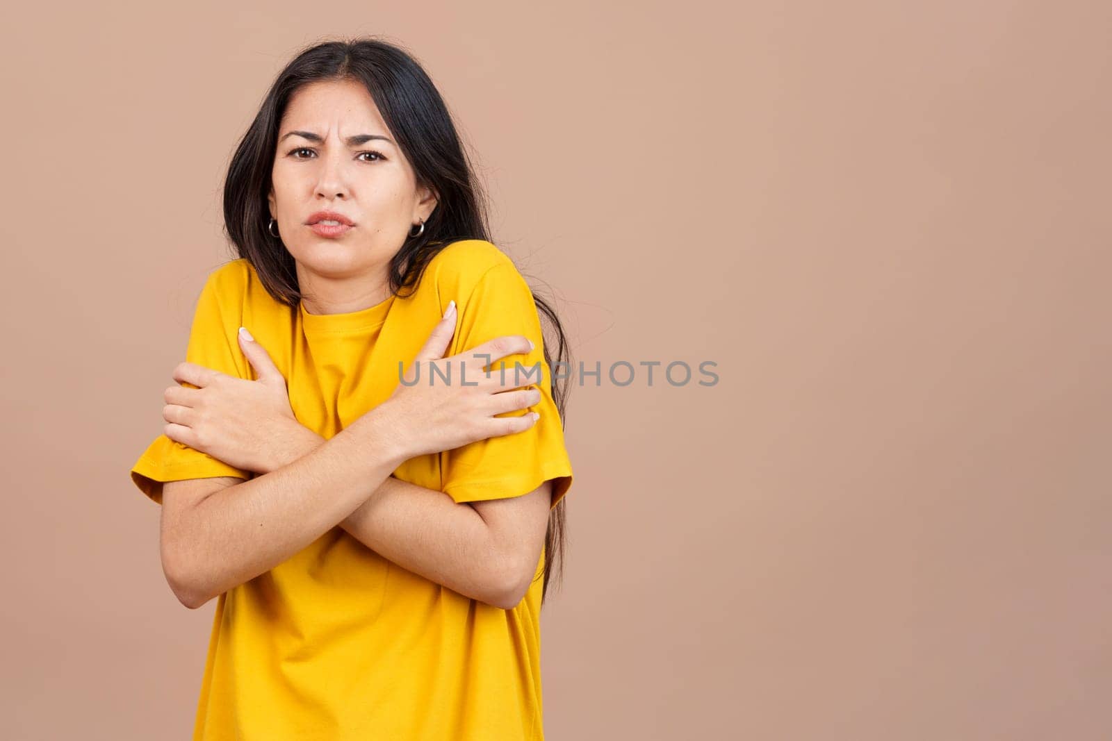 Caucasian woman looking at camera gesturing in cold in studio with brown background