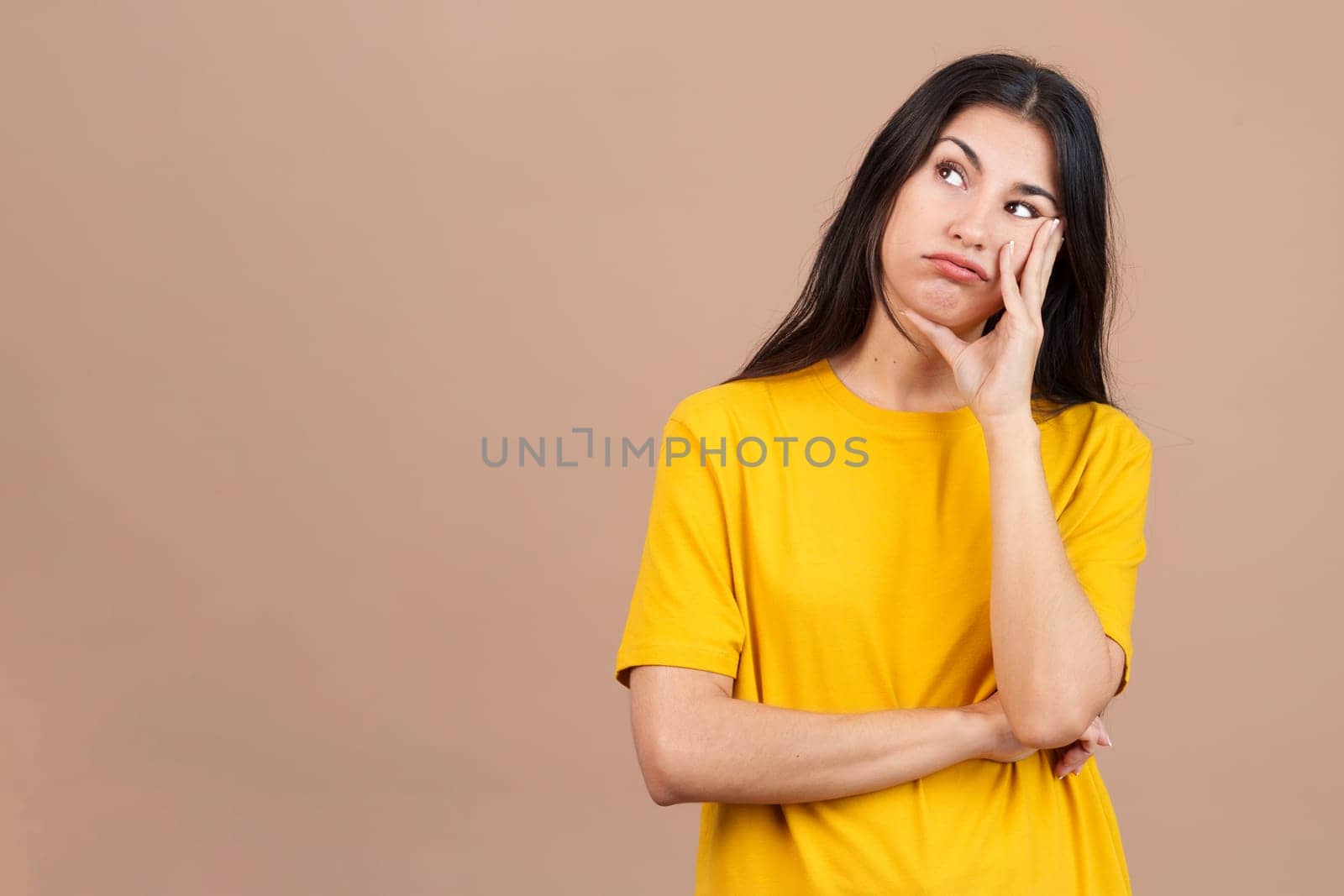 Bored caucasian woman standing and looking up in studio with brown background