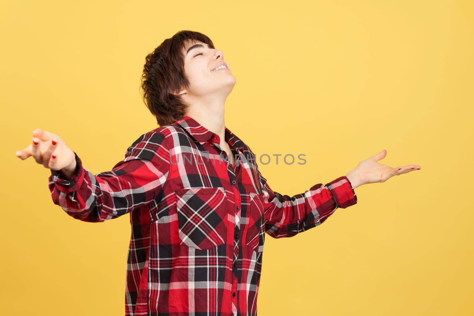 Androgynous person taking a deep breath gesturising wellbeing in studio with yellow background