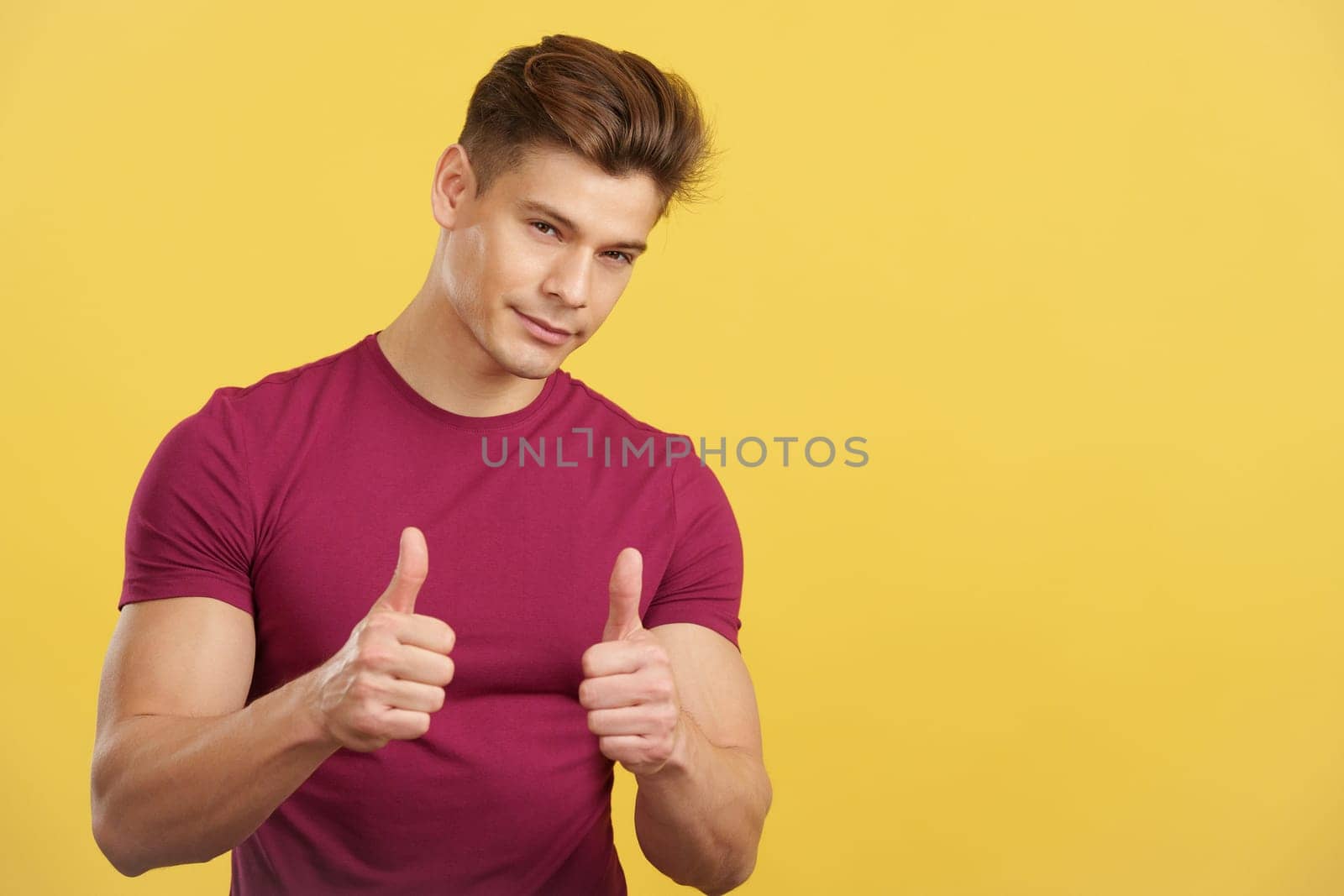 Man gesturing approval with the thumb up in studio with yellow background