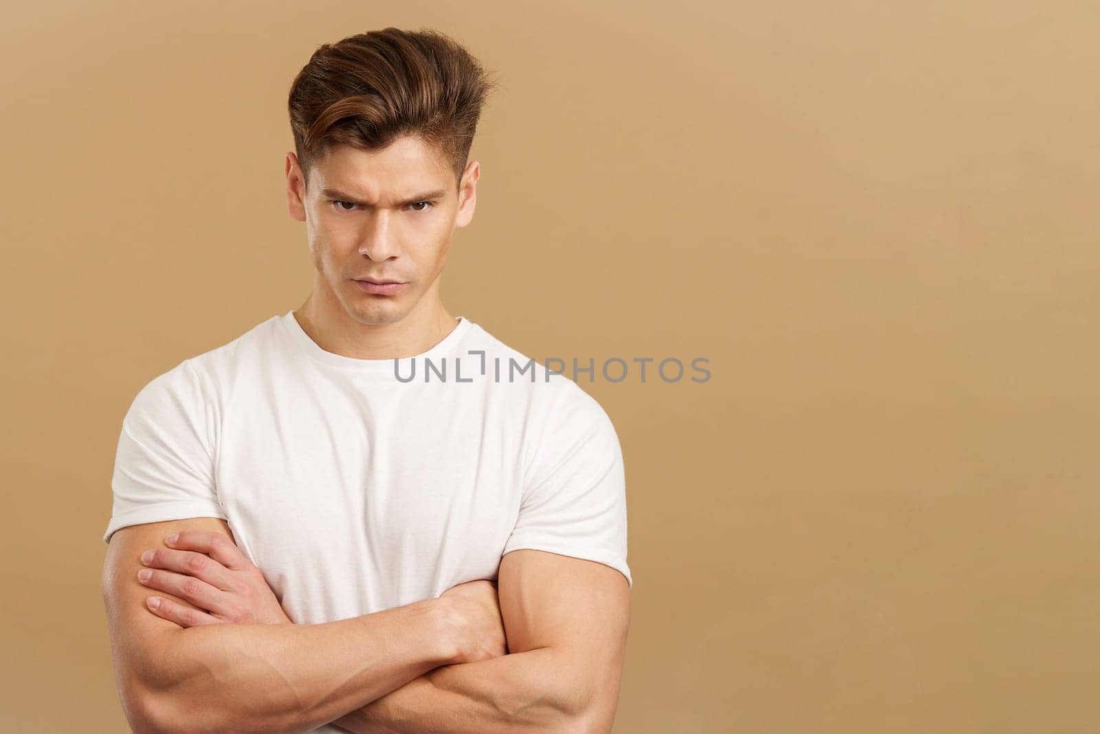 Strong man looking the camera with an angry expression in studio with brown background