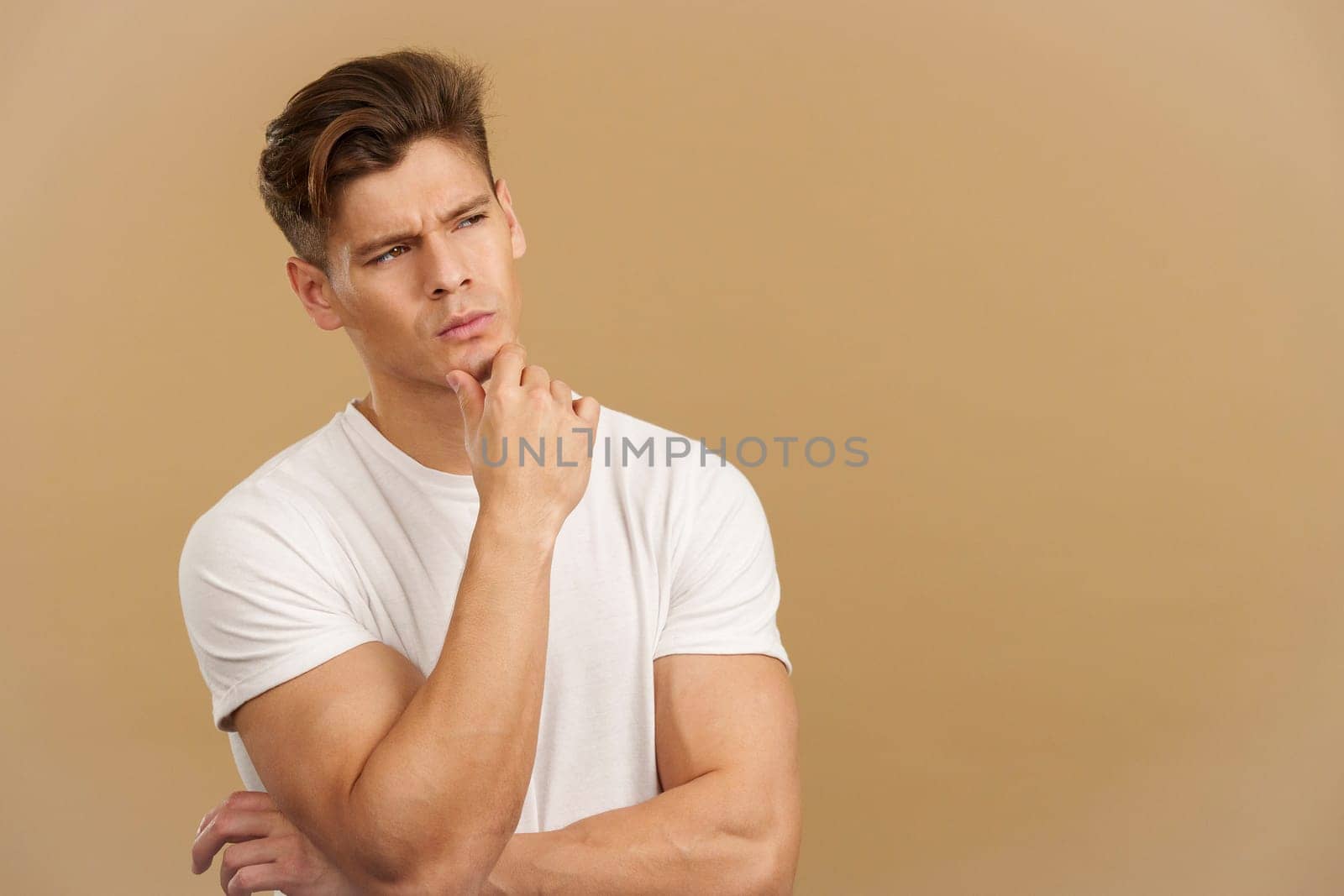 Man with hand on face and thoughtful expression in studio with brown background