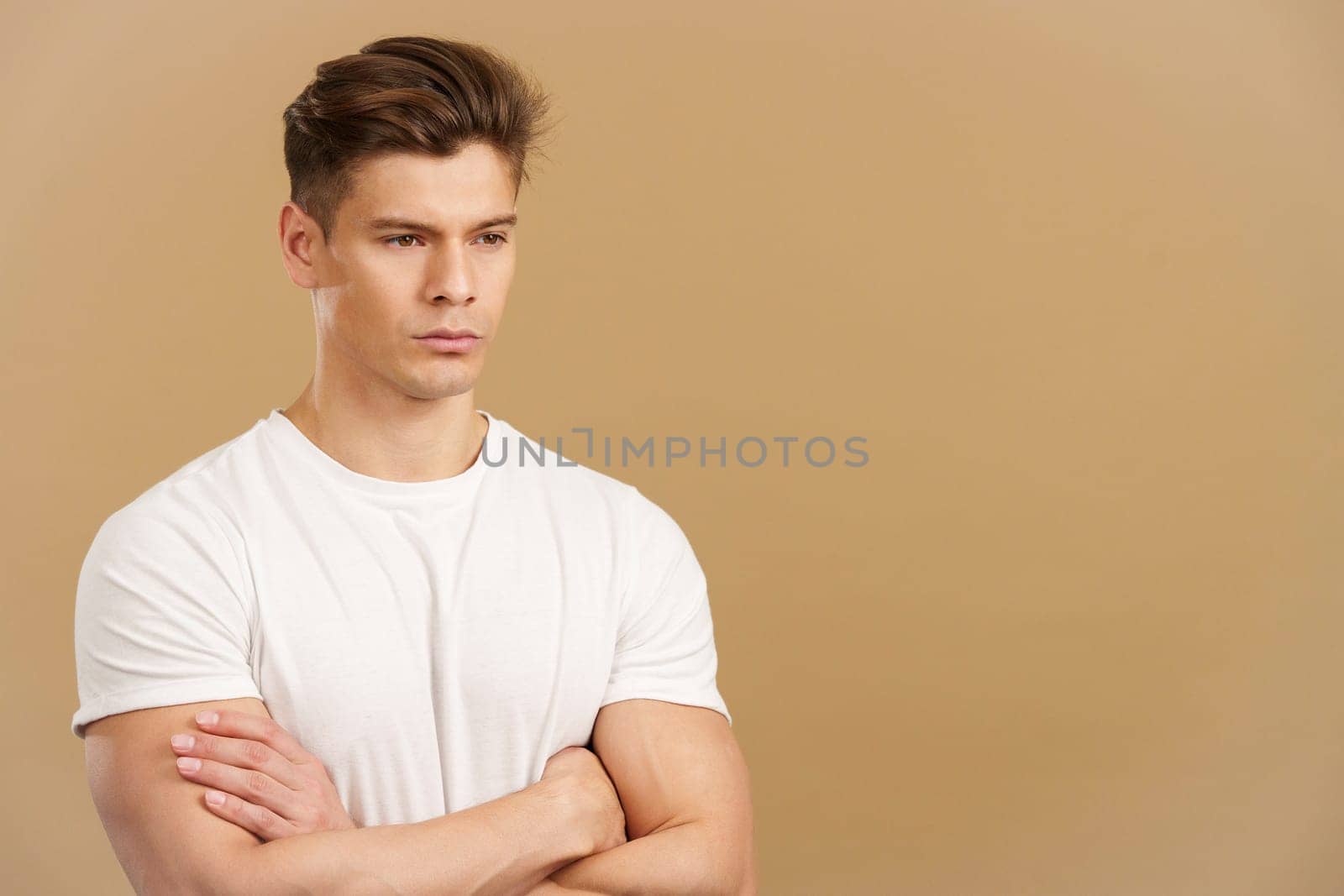 Handsome man crossing the arms with an angry expression in studio with brown background