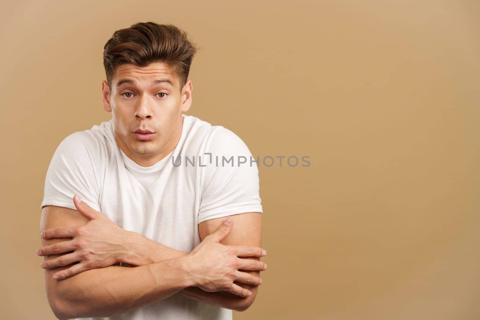 Man looking at camera woman gesturing he is cold in studio with brown background