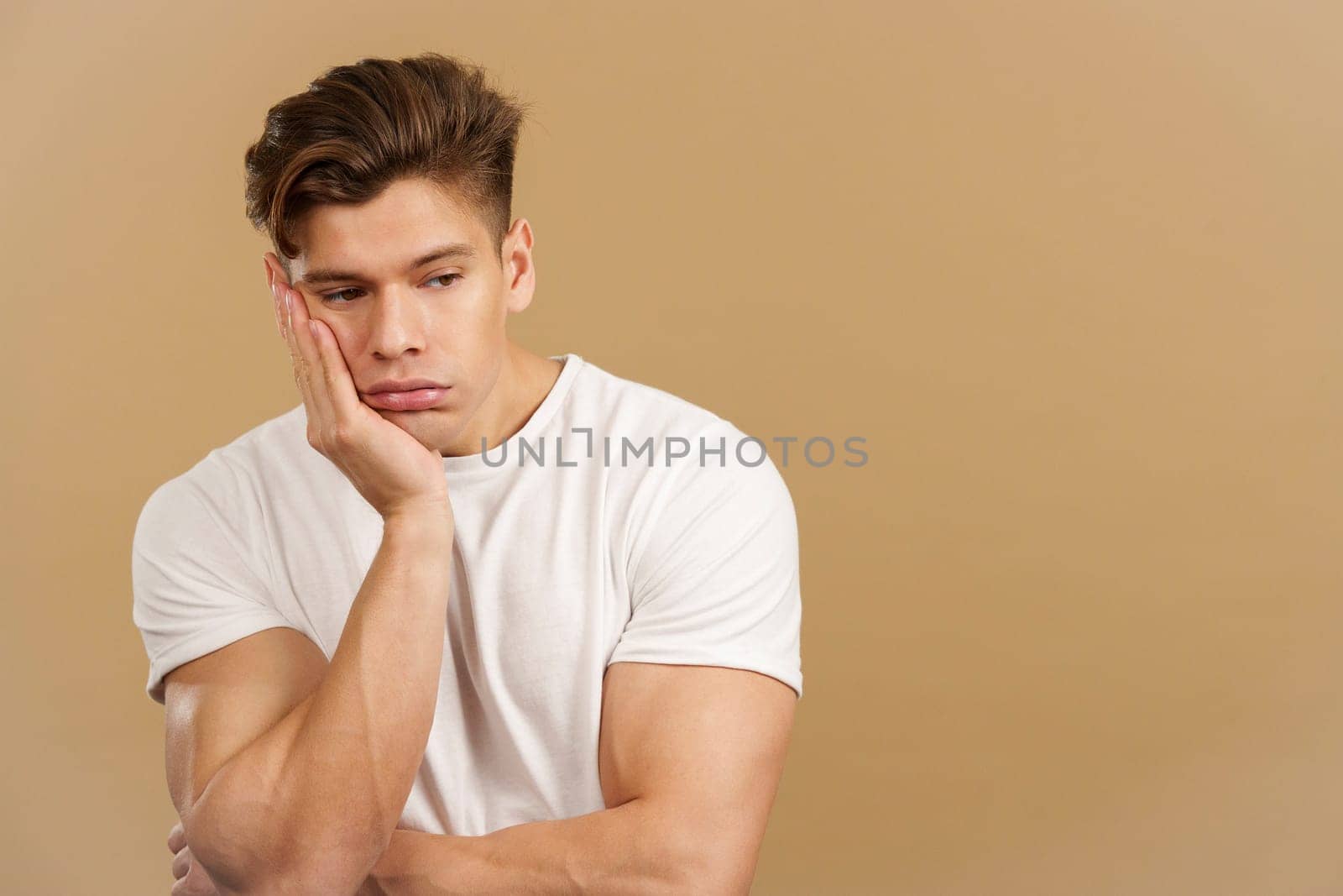 Bored caucasian man with the hand on the face in studio with brown background