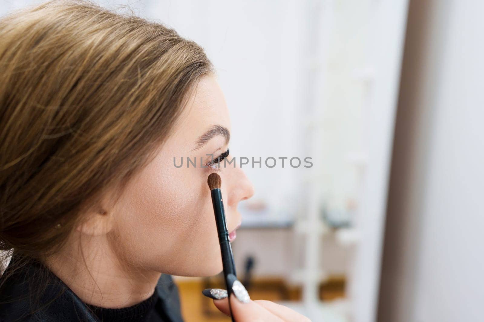 Close up portrait of the profile of a woman applying eye shadow on a backstage