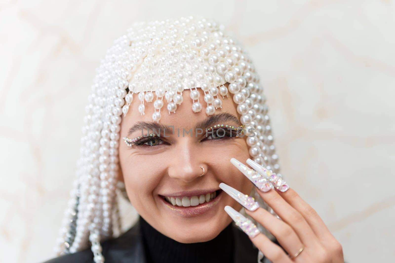 Close up portrait of a happy woman smiling at camera with make up and a wing of pearls, glitter and fake nails