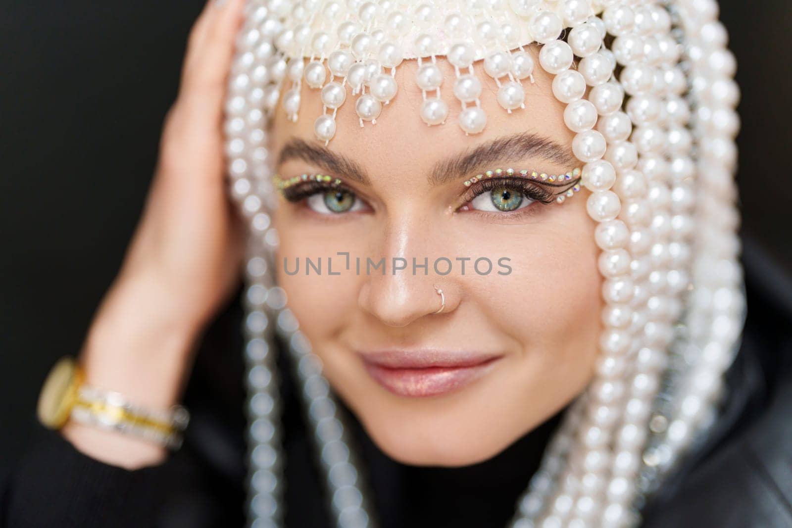 Portrait of a happy female artist with a wig of pearls and make up in studio