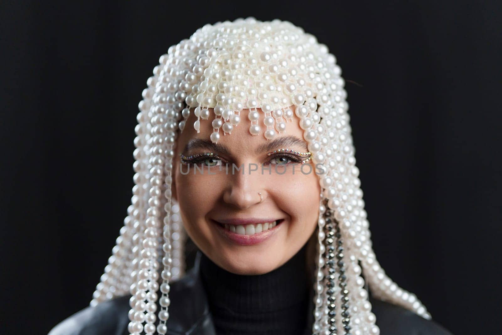 Happy woman with make up and a wing of pearls in studio