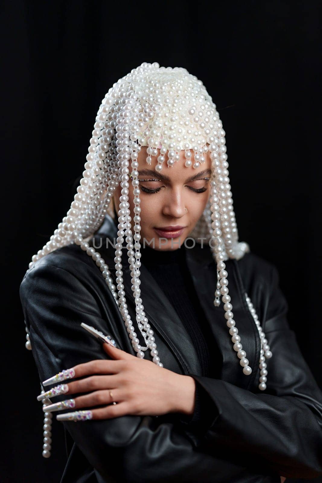 Studio portrait of a concentrated woman with fantasy costume with fake nails and a wig of pearl