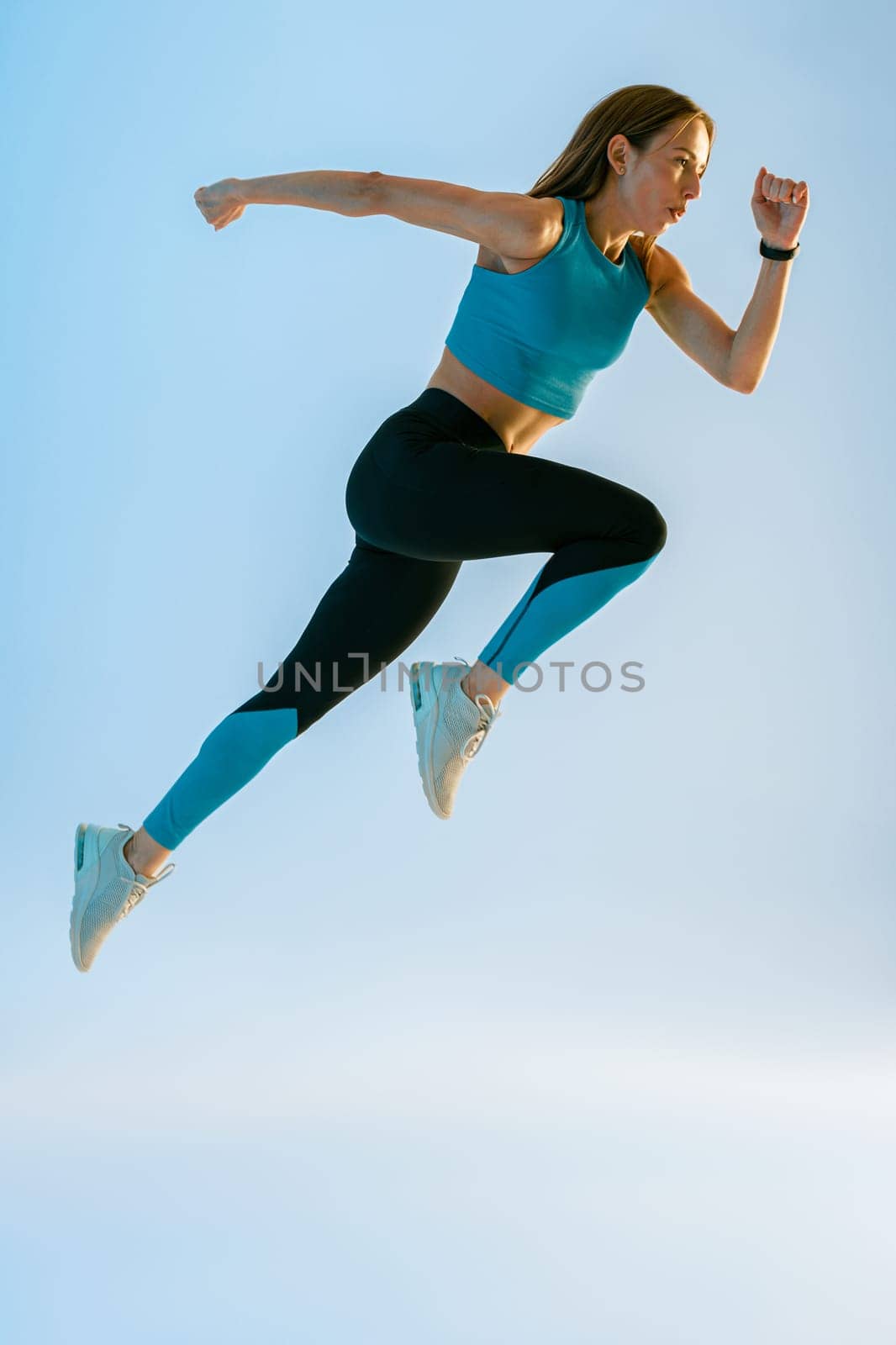 Determined sporty woman running in Mid-Air exercising during cardio workout over studio background by Yaroslav_astakhov
