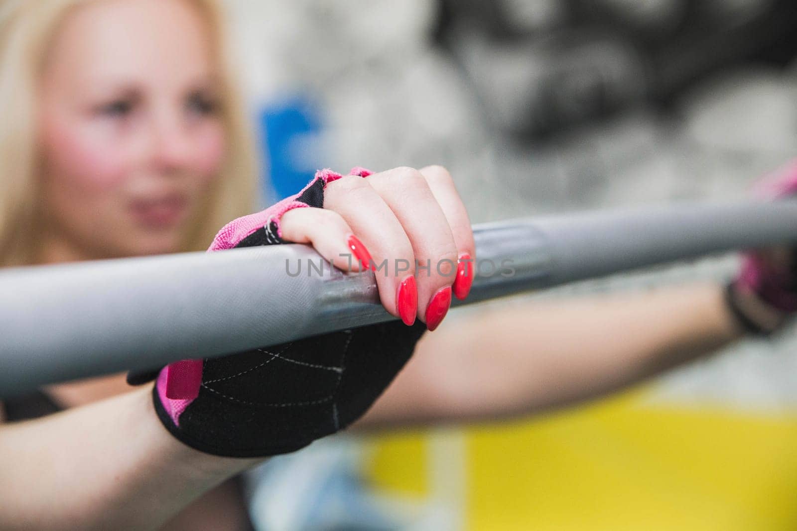 Hands with red nail polish on the barbell.