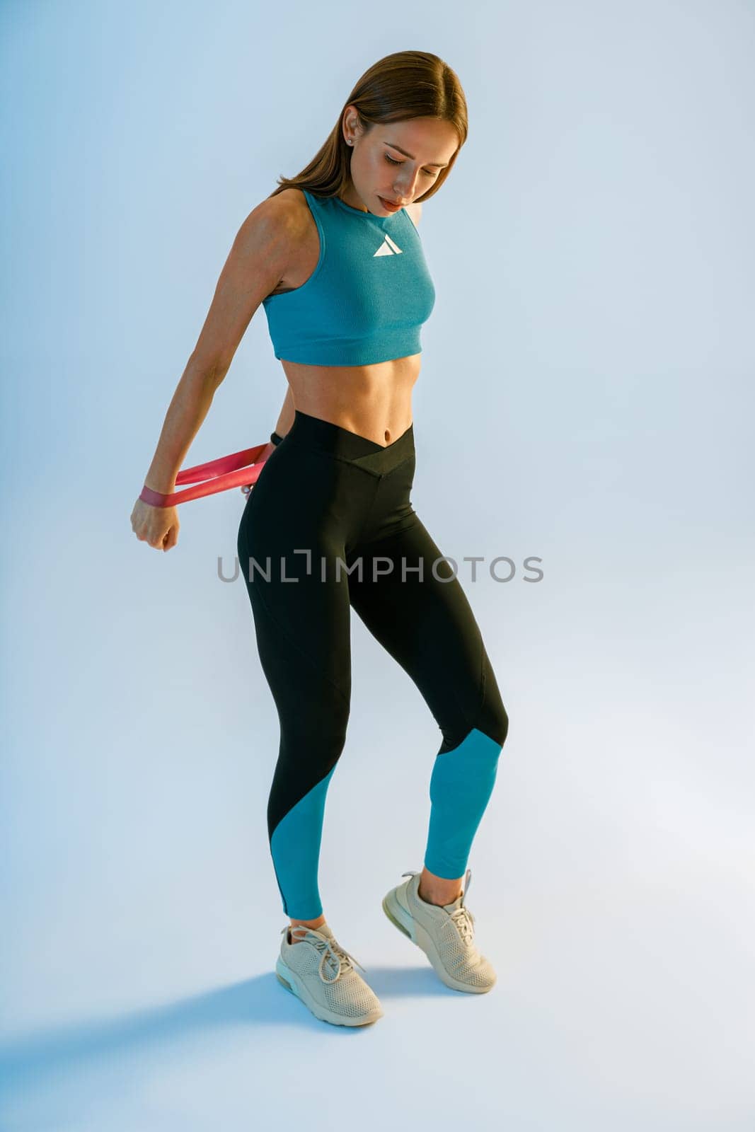 Sports woman with her hands stretches rubber elastic band on studio background. High quality photo