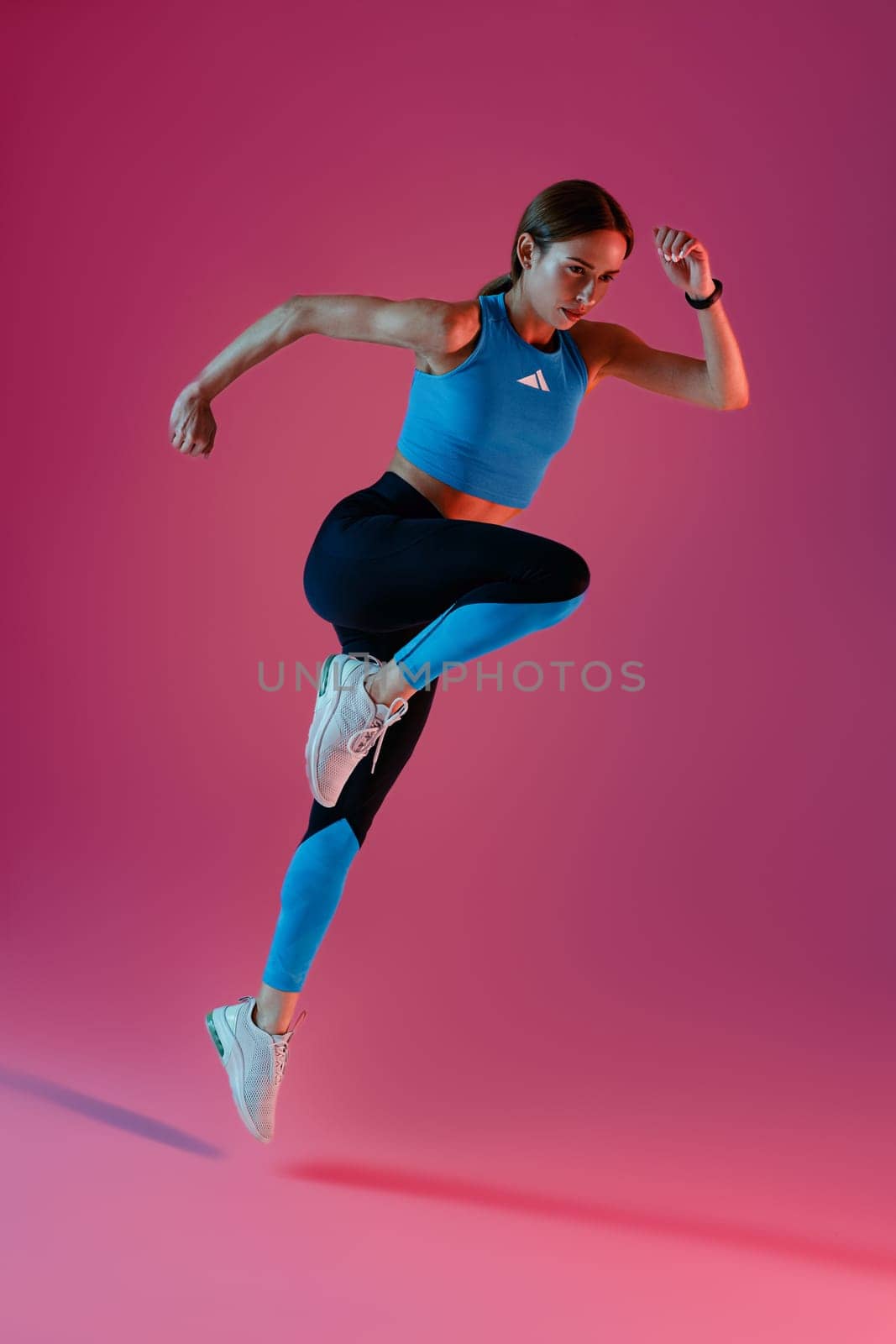 Woman running in Mid-Air exercising during cardio workout over studio background. High quality photo