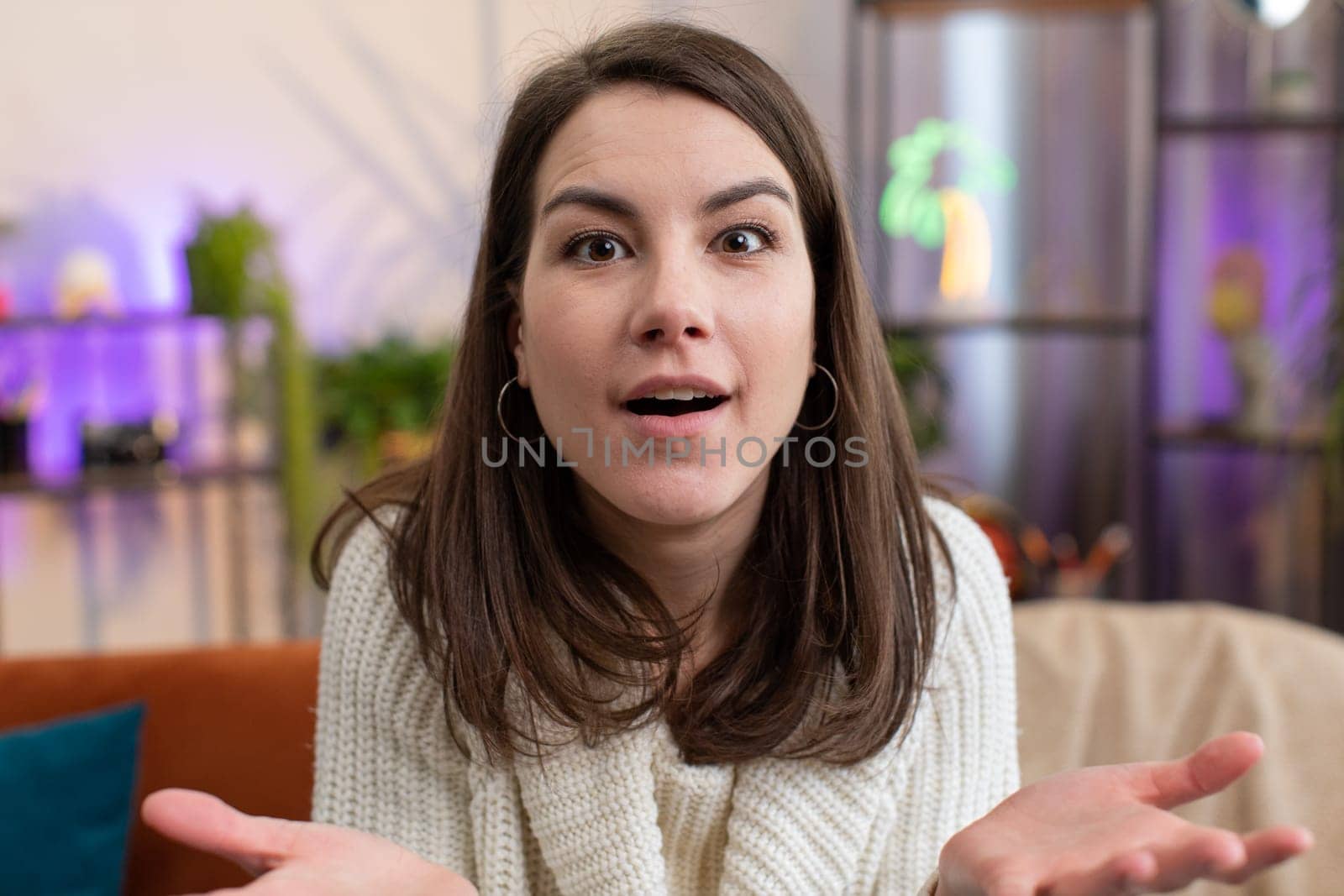 Oh my God, Wow. Portrait of young woman surprised looking at camera with big eyes, shocked by sudden victory, good win news, celebrating at home room apartment. Excited amazed girl sitting on couch