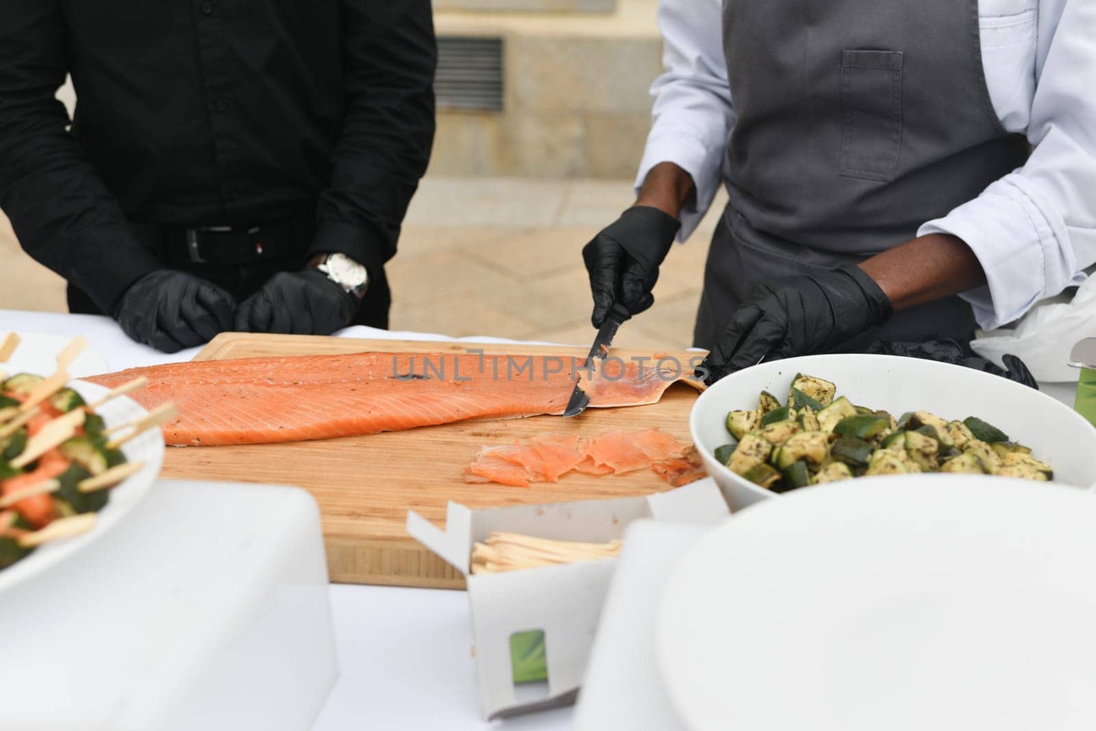 Cooks cut salmon fish at a wedding