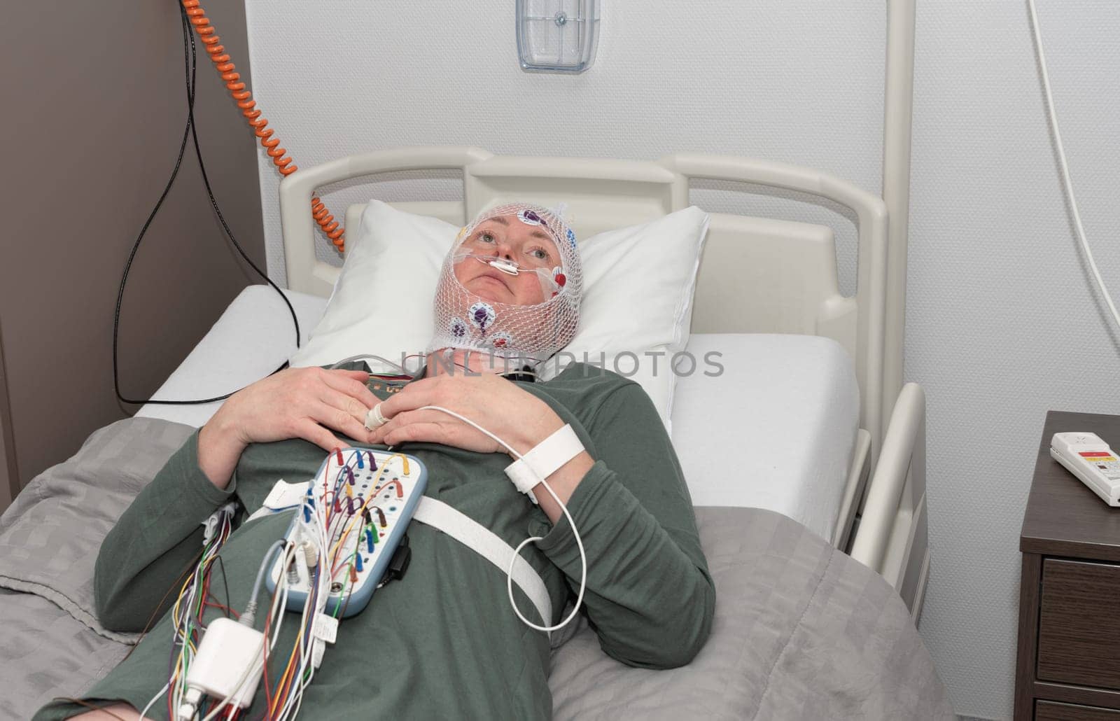 Middle aged woman measuring brain waves, examining polysomnography in sleep lab by KaterinaDalemans